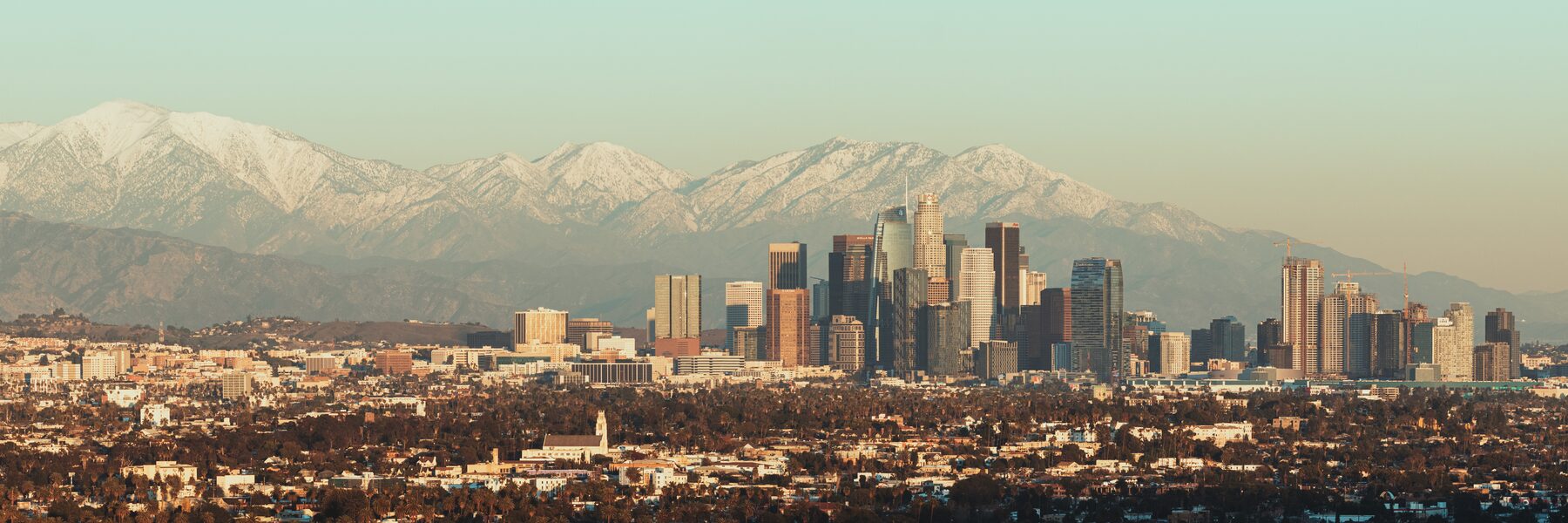 Panorama of the Los Angeles basin running to a snow-capped mountain range.
